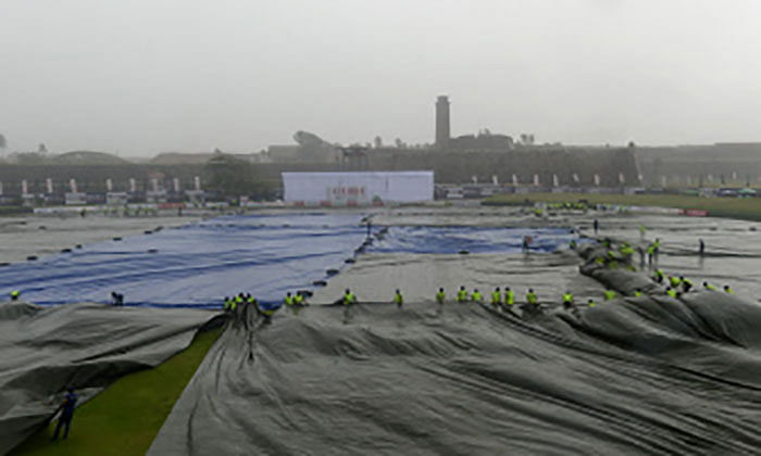 Ground staff cover the pitch as rain showers stop the play during the first day of the opening Test cricket match between Sri Lanka and New Zealand at the Galle International Cricket Stadium in Galle on Wednesday. Photo: AFP