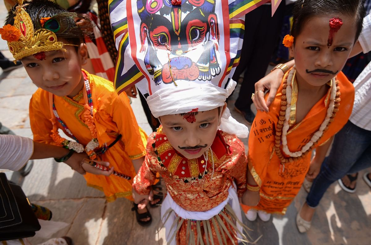 A Nepali child (C) dressed in a traditional cow costume poses with others as they take part in a procession for the Gai Jatra cow festival in Kathmandu on 16 August, 2019. Photo: AFP
