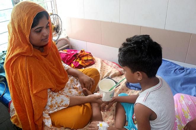 A dengue-infected child drinks milk with a straw in Shaheed Ziaur Rahman College Hospital in Bogura on 16 Aug, 2019. Photo: Soel Rana