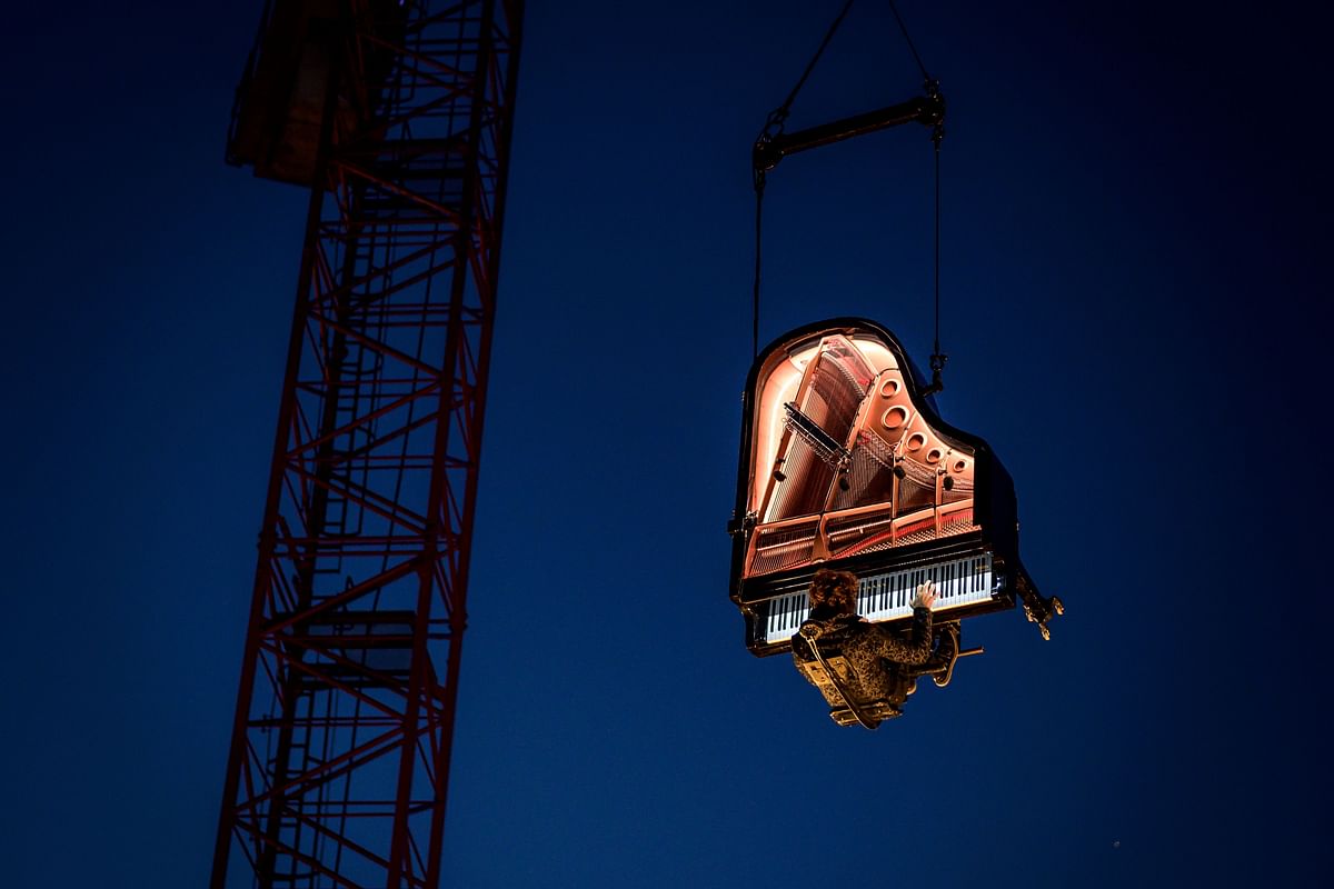 Swiss pianist and composer Alain Roche performs “Chantier” suspended in the air with his grand piano under a moving crane at dawn on 16 August, 2019 during the 20th `Jeux du Castrum`, a multidisciplinary festival that takes place until 18 August, 2019 in Yverdon-les-Bains. Photo: AFP