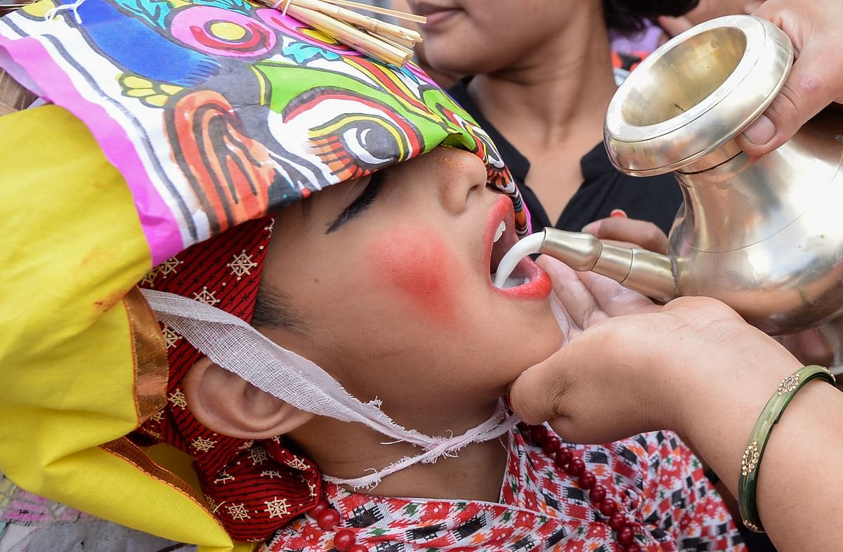 A Nepali woman pours milk into a boy`s mouth during a procession for the Gai Jatra cow festival in Kathmandu on 16 August, 2019. Photo: AFP