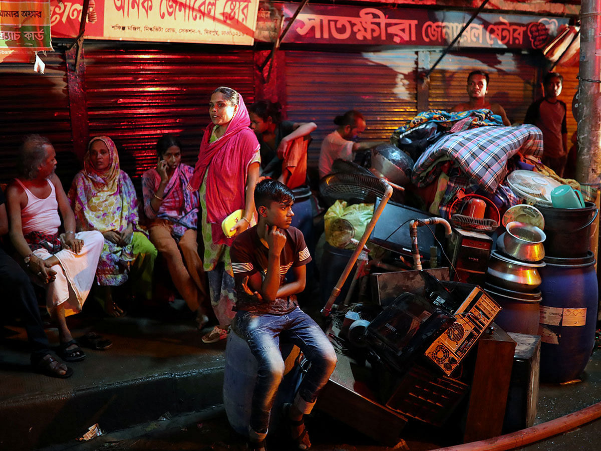Slum dwellers sit on the street with their belongings as fire broke out on their shelters in Dhaka, Bangladesh, 16 August 2019. Photo: Reuters