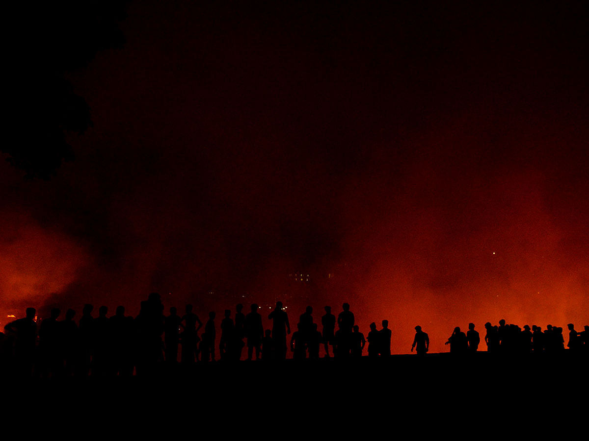 Bangladeshi onlookers gather after a fire blazes in a slum in Dhaka on 16 August 2019. Photo: AFP