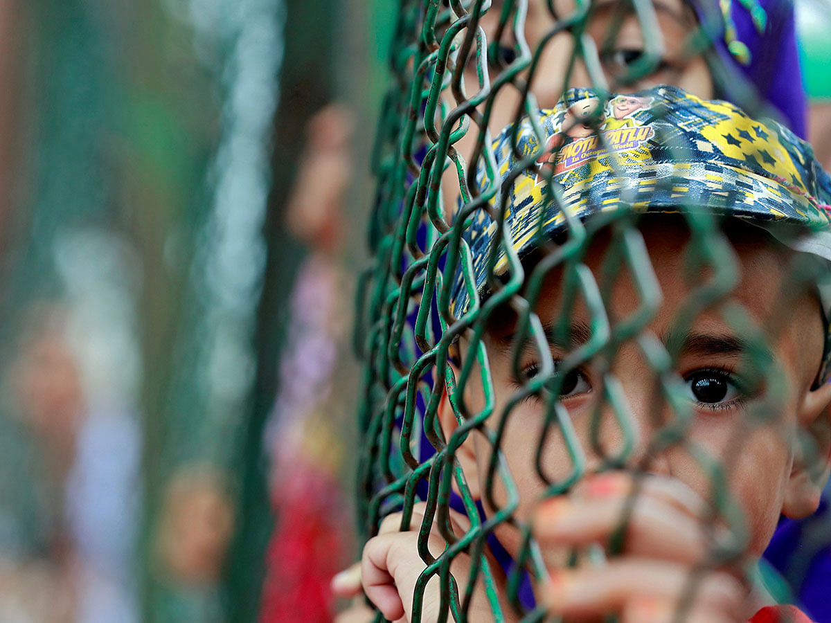 Kashmiri child looks from behind a fence at a protest site after Friday prayers during restrictions after the Indian government scrapped the special constitutional status for Kashmir, in Srinagar, 16 August 2019. Photo: Reuters