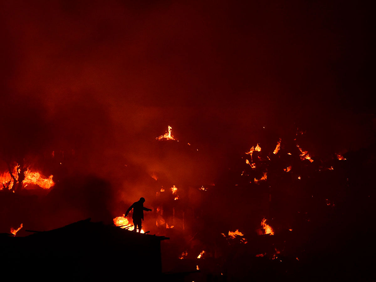 Bangladeshi man tries to extinguish a fire as a fire blazes in a slum in Dhaka on 16 August 2019. Photo: AFP