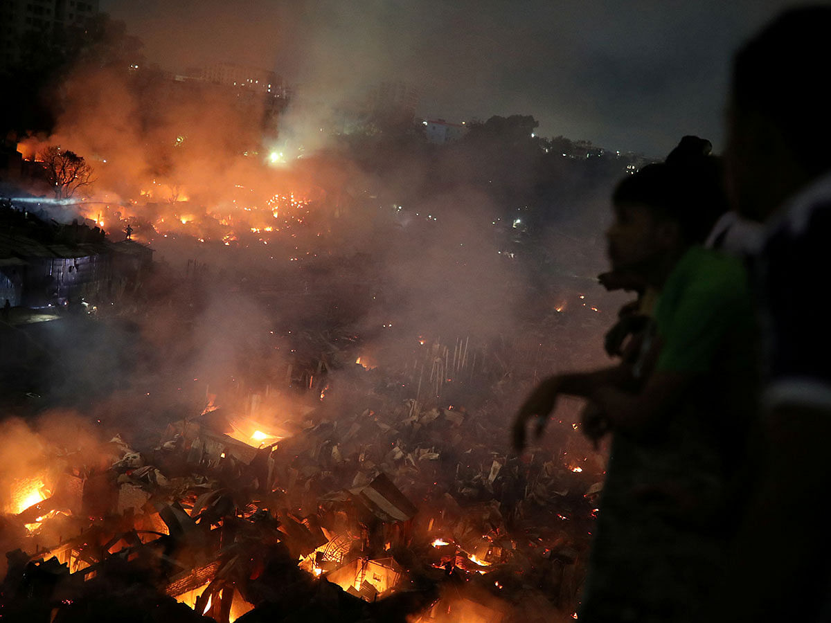 People gather at a rooftop to watch the fire that broke out at a slum in Dhaka, Bangladesh, 16 August 2019. Photo: Reuters