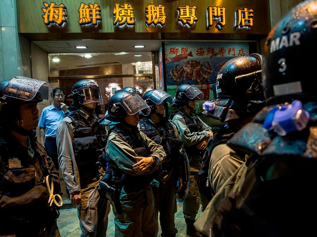 Riot police stand in front of a restaurant while patrolling after an anti-government rally in Hong Kong on 18 August in the latest opposition to a planned extradition law that has since morphed into a wider call for democratic rights in the semi-autonomous city. Photo: AFP