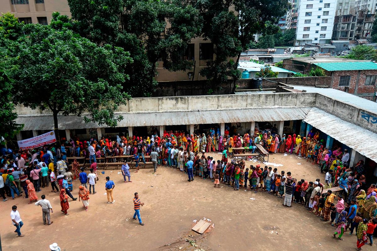Slum residents queue up for food in Dhaka on 18 August 2019, after a fire broke out late on 17 August in a slum at Mirpur neighbourhood. Photo: AFP