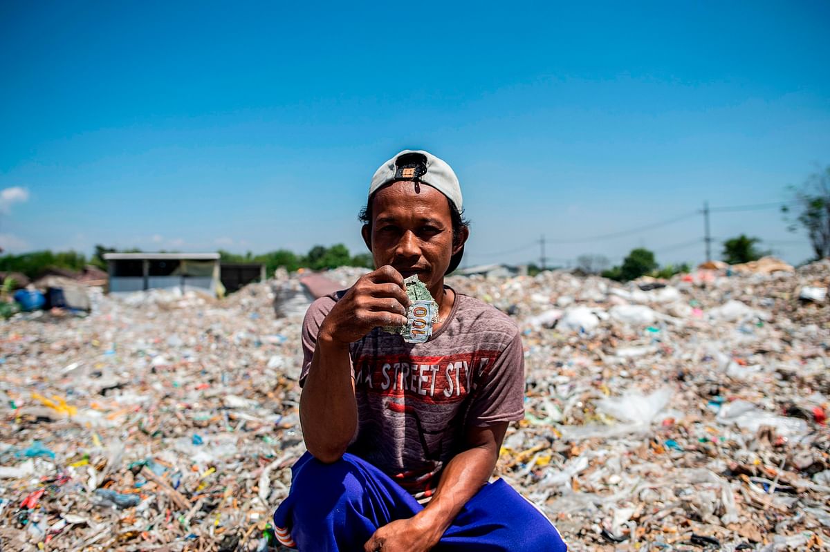 This picture taken on 22 July, 2019 shows villager Keman sitting amongst plastic waste in the village of Bangun. Photo: AFP