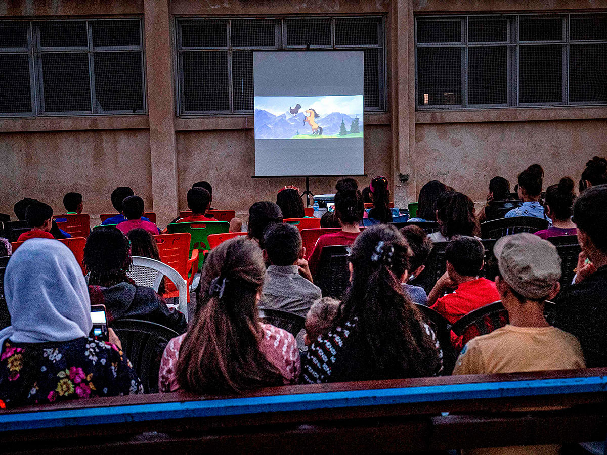 Children attend a film screening as part of the mobile cinema `Komina Film` initiative organised by Syrian-Kurdish filmmaker Shero Hinde, at a school yard in the village of Shaghir Bazar, 55 kilometres southeast of Qamishli in the Kurdish-populated areas of north-eastern Syria`s Hasakeh province, on 28 July, 2019. Photo: AFP