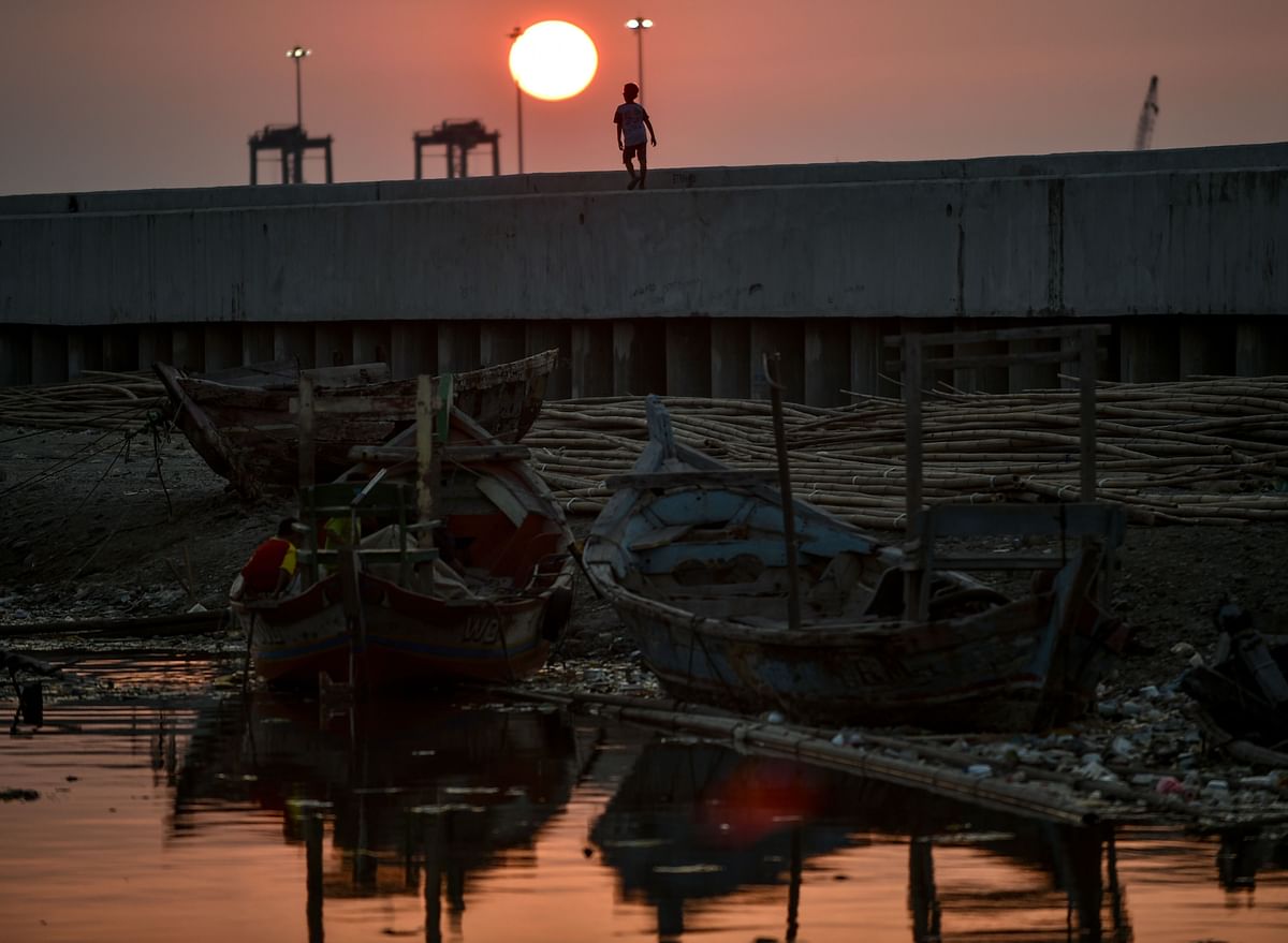 In this picture taken on 12 July 2019 a boy is walking on the top of a giant sea wall in northern Jakarta, during sunset. Photo: AFP