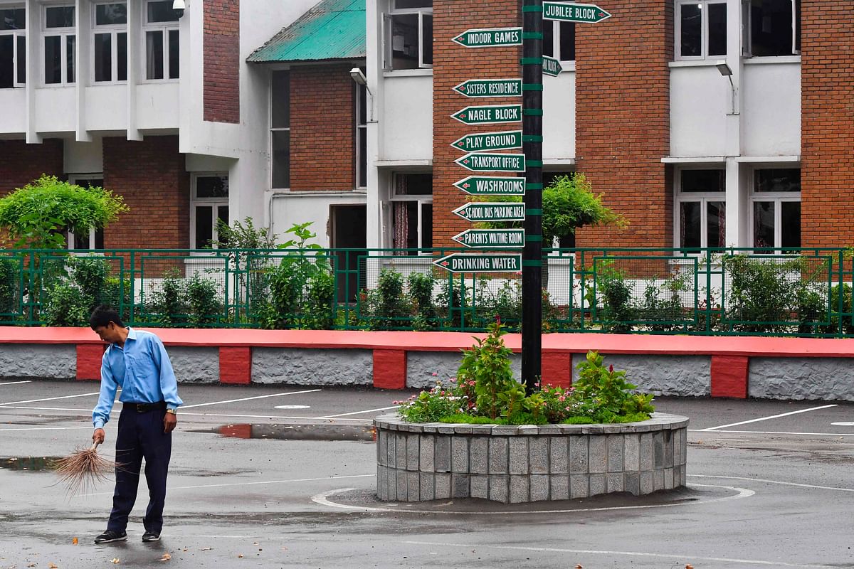 A worker cleans the campus of an empty school in Srinagar on 19 August 2019. Photo: AFP