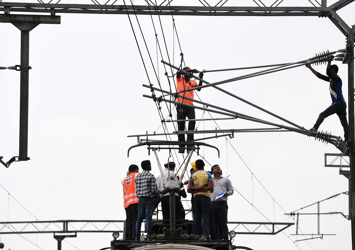 Officials and ground staff inspect an electric train track in New Delhi on 19 August 2019. Photo: AFP