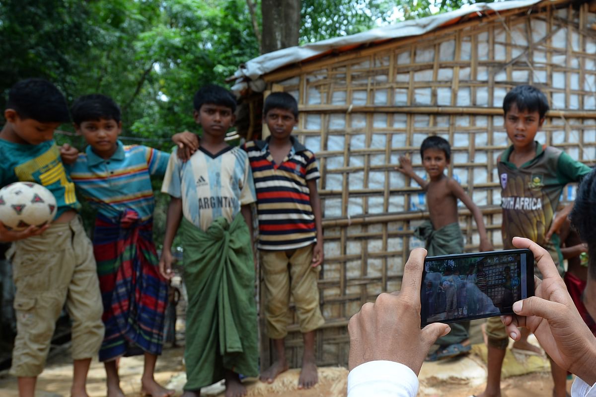 In this picture taken on 23 July 2019, children pose as Rohingya youth Mohammad Rafiq takes their photos with a mobile phone at the Kutupalong refugee camp. Photo: AFP