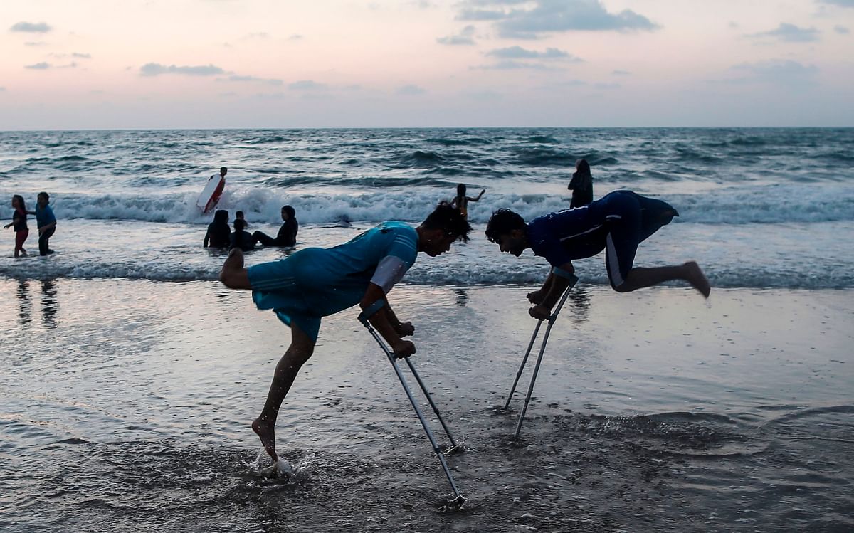 Palestinian amputees Mohammed Eliwa, 17, and Ahmed al-Khoudari (R), 20, who lost their legs during clashes on the border with Israel, play on the beach in Gaza City on 20 August 2019. Photo: AFP
