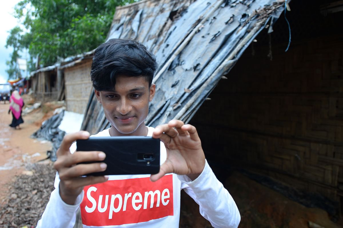 In this picture taken on 23 July 2019, Rohingya youth Mohammad Rafiq uses his mobile phone to take photos at the Kutupalong refugee camp. Photo: AFP