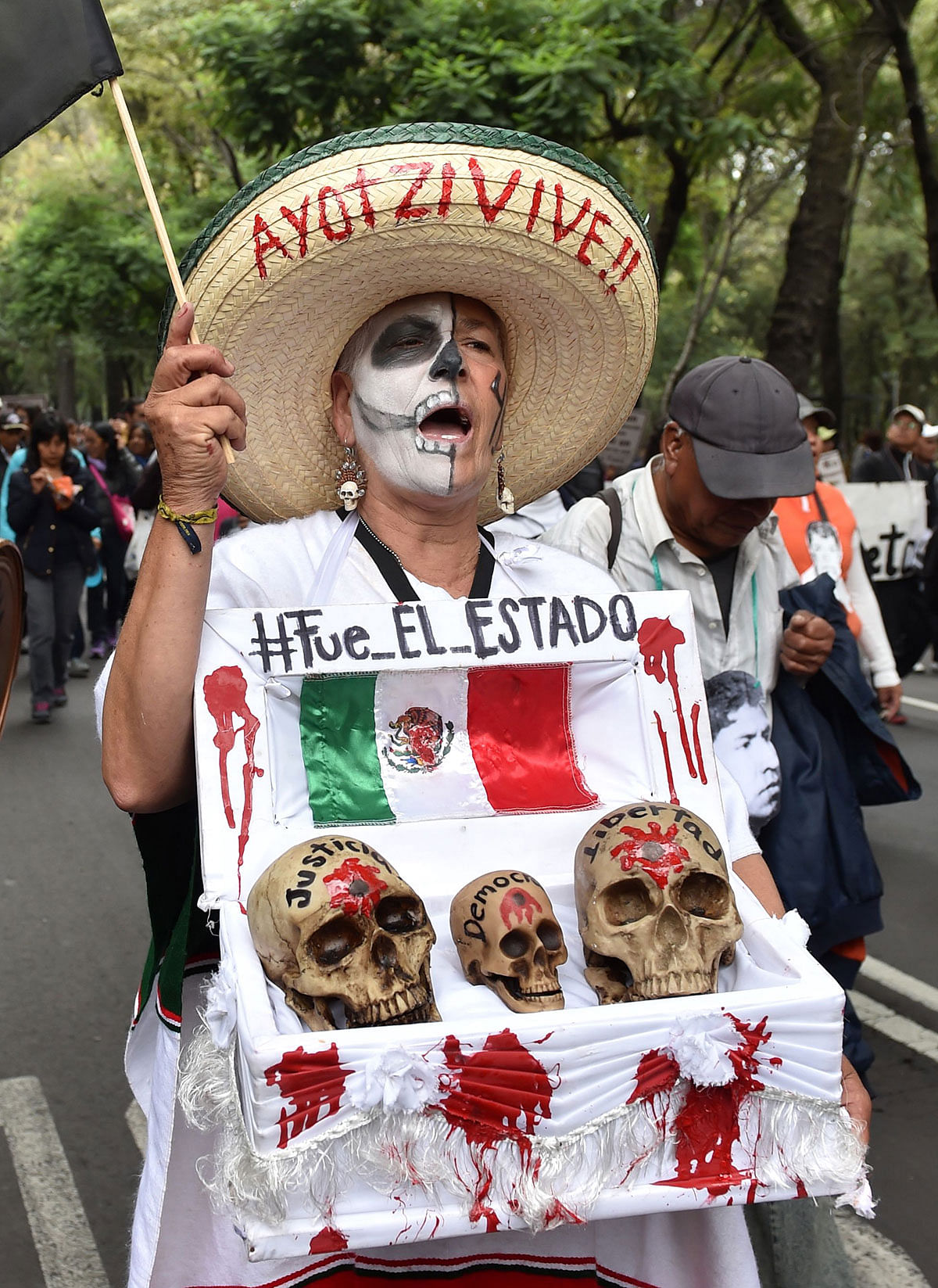 In this file photo taken on 26 September 2015 Mexican activist Julia Klug holds a fake coffin with skulls captioned `Justice, Democracy and Freedom` and a sign reading `It was the State` during a protest in Mexico City, commemorating the first anniversary of the disappearance of the Ayotzinapa students. Photo: AFP