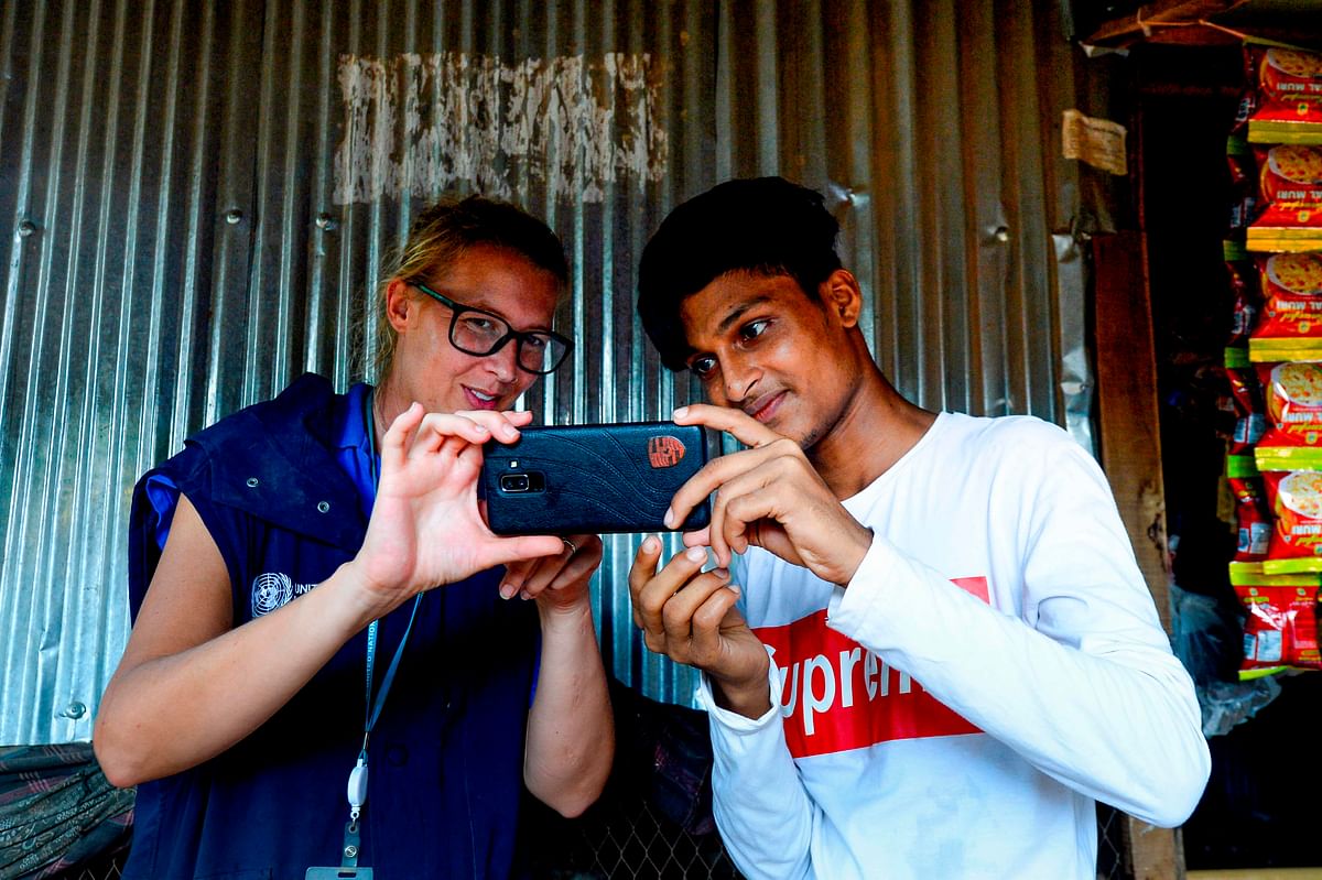 In this picture taken on 23 July 2019, World Food Programme (WFP) official Gemma Snowdon (L) coaches Rohingya youth Mohammad Rafiq on methods to take better photos with his mobile phone at the Kutupalong refugee camp. Photo: AFP