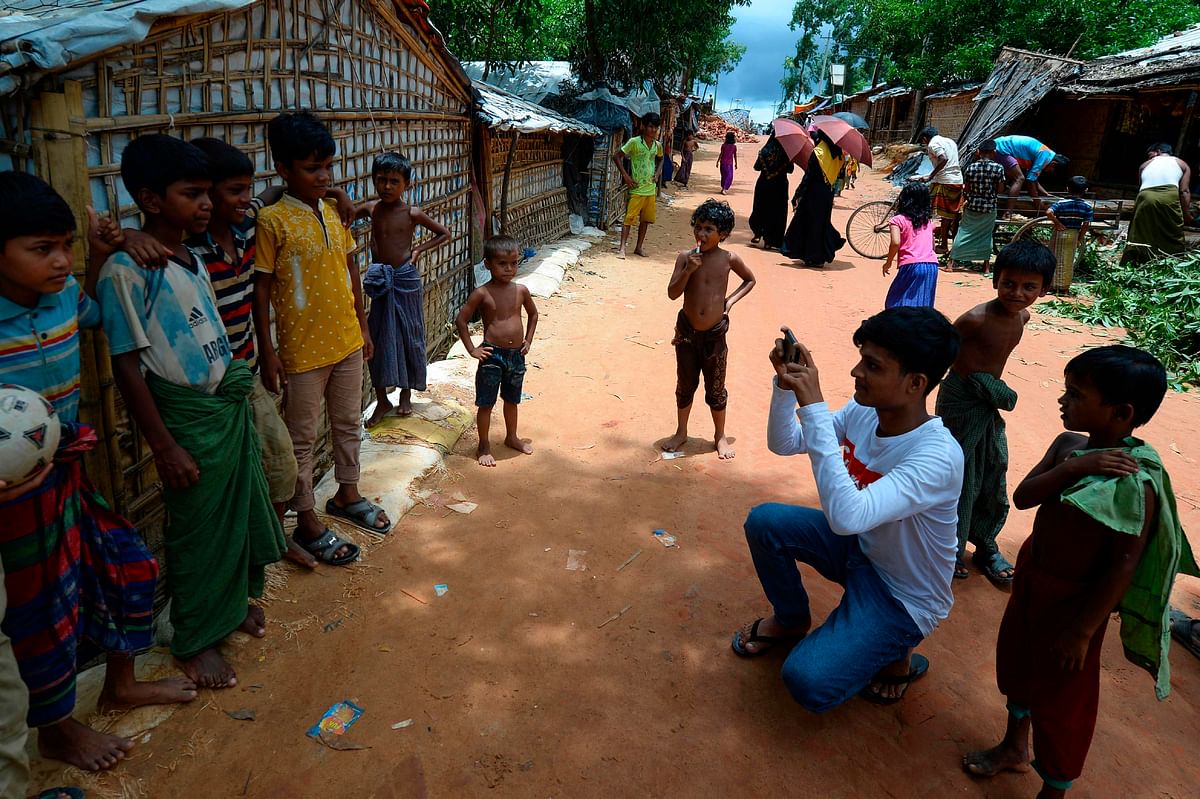 In this picture taken on 23 July 2019, Rohingya youth Mohammad Rafiq (2nd R, in white) uses his mobile phone to take photos of children at the Kutupalong refugee camp. Photo: AFP