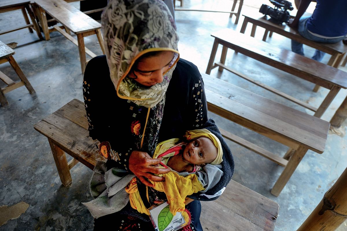 This photograph taken on 23 July 2019, shows a mother helping to weigh her newborn baby who is suffering various physical problems including severe respiratory disease at a field hospital in a Rohingya refugee camp in Ukhia in southern Bangladesh. Photo: AFP
