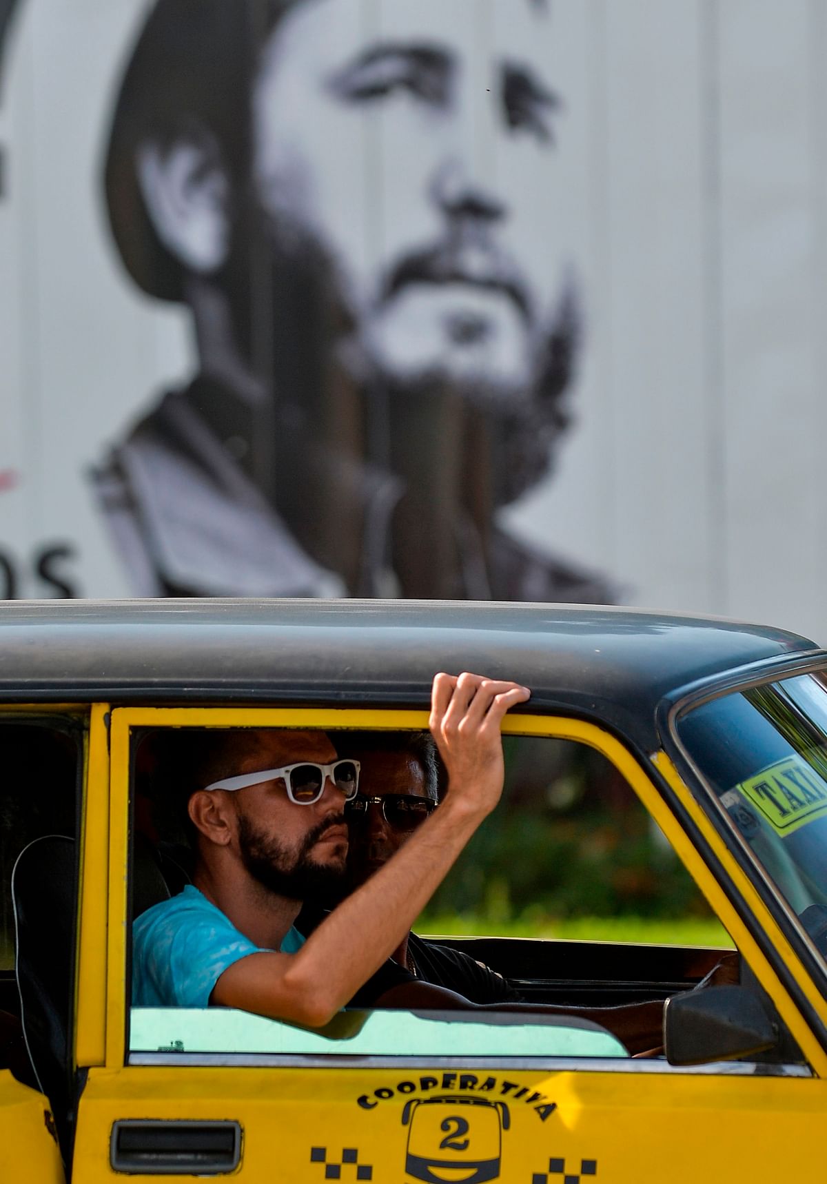A man with a beard travels in a taxi in front of a poster with the image of Cuban late leader Fidel Castro in Havana, on 16 July 2019. Photo: AFP