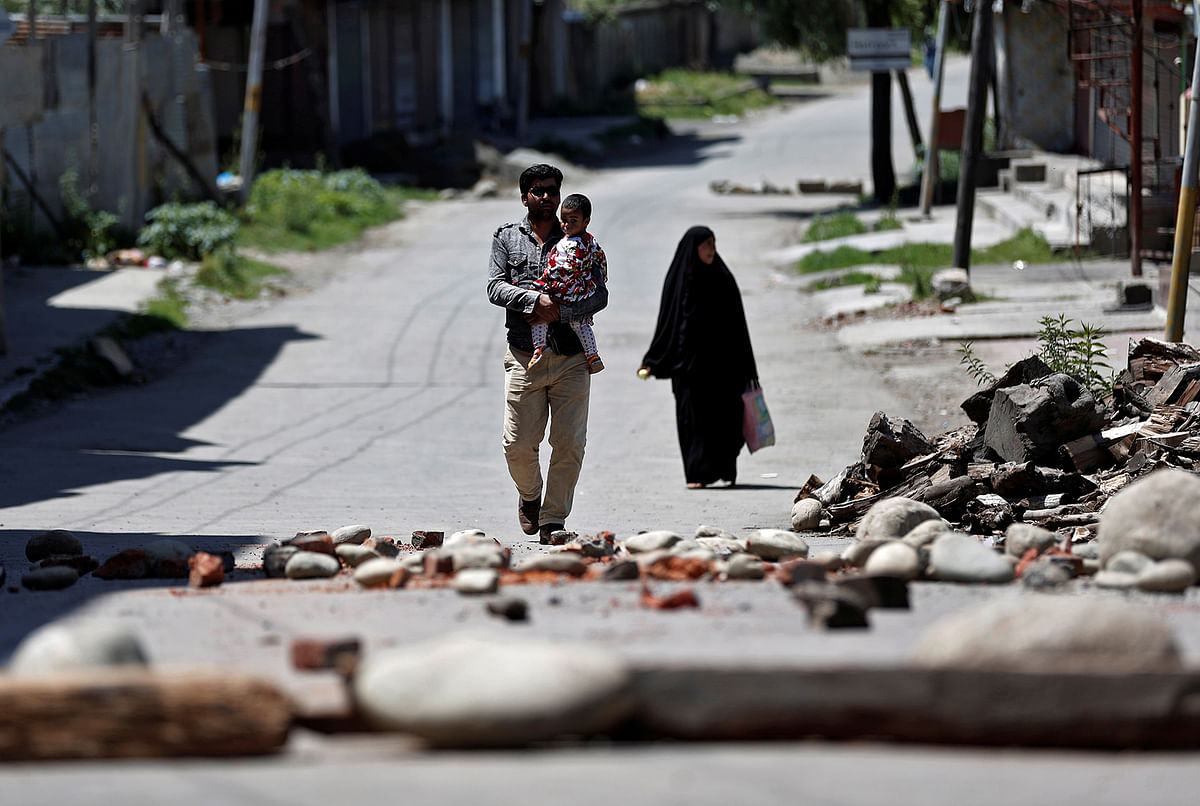 A Kashmiri familiy walks past a blockade put up by residents to prevent Indian security force personnel from entering their neighborhood during restrictions, after the scrapping of the special constitutional status for Kashmir by the Indian government, in Srinagar, 20 August, 2019. Photo: Reuters.