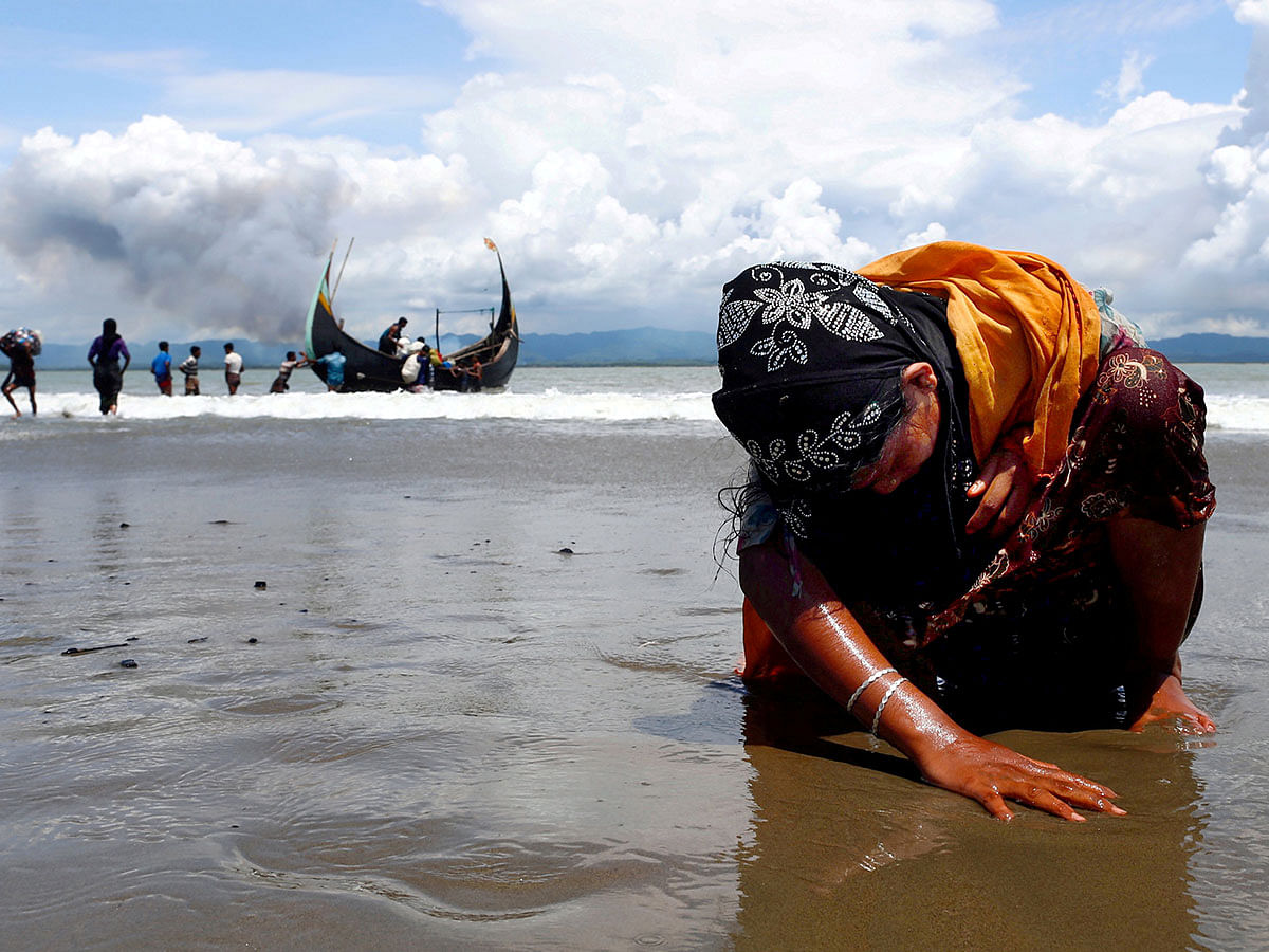 An exhausted Rohingya refugee woman touches the shore after crossing the Bangladesh-Myanmar border by boat through the Bay of Bengal, in Shah Porir Dwip, Bangladesh on 11 September 2017. Reuters File Photo
