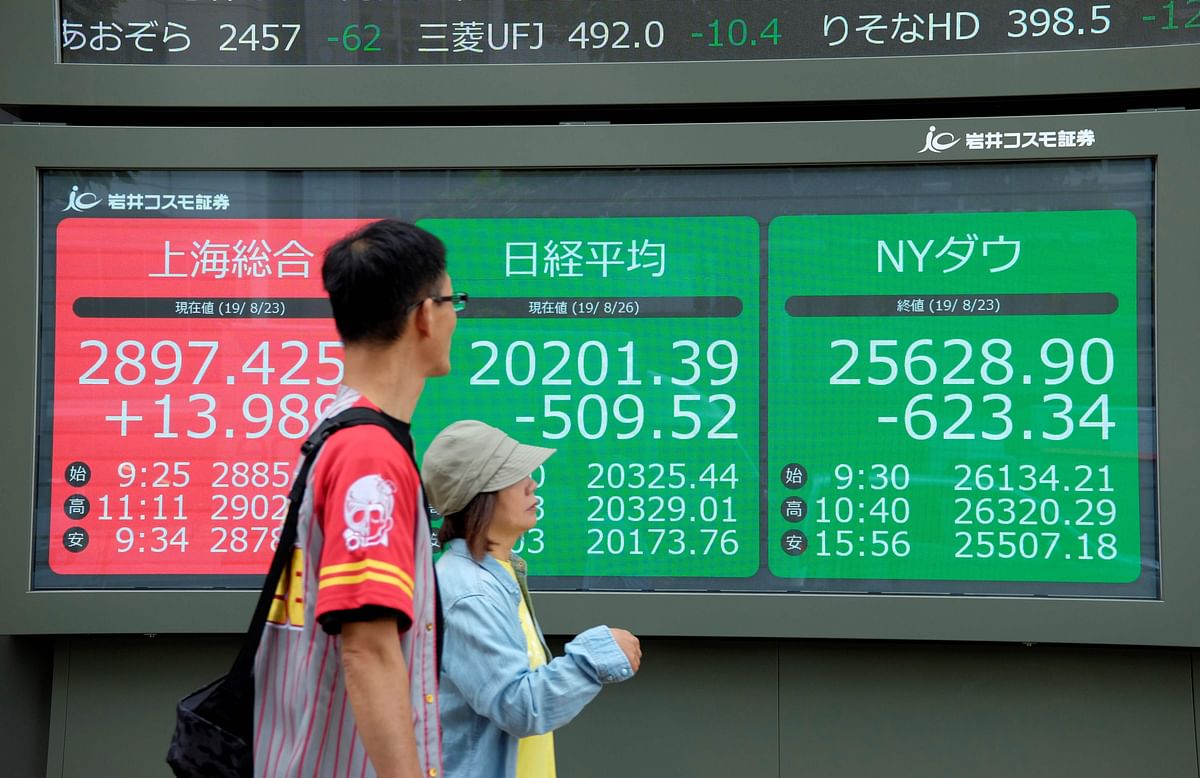 Pedestrians walk in front of an electric quotation board displaying the numbers oF the Nikkei 225 index at the Tokyo Stock Exchange (C), the Shanghai Stock Exchange (L) and New York Dow (R) in Tokyo on Monday. Photo: AFP