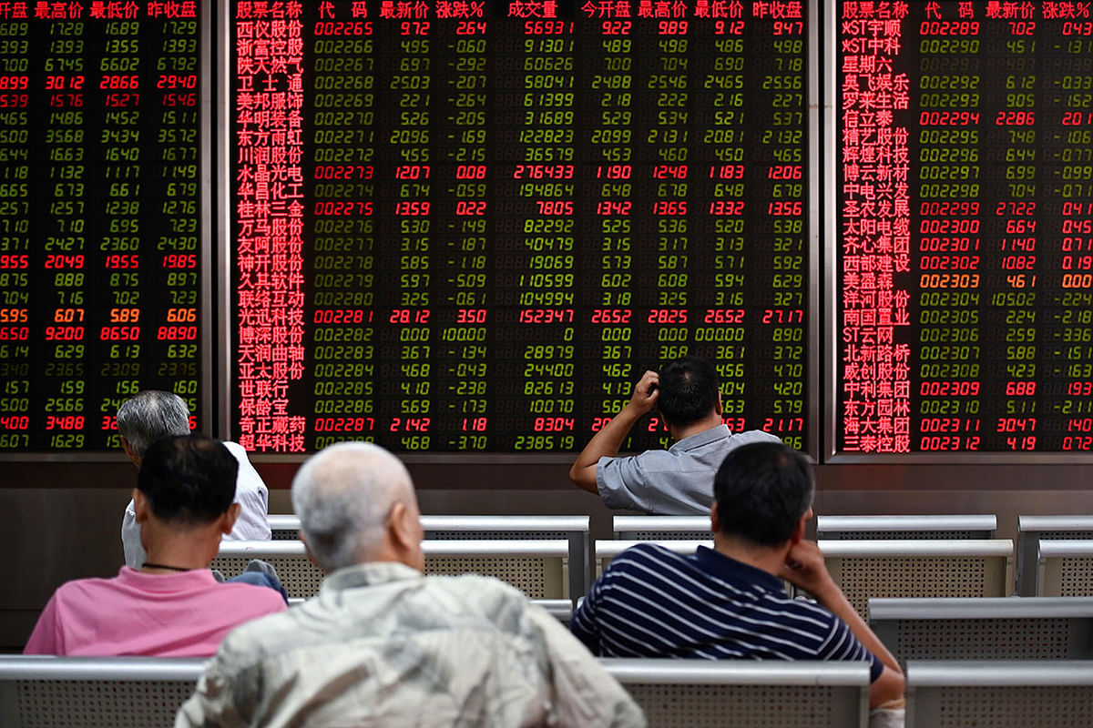 Investors rest on a chair in front of screens showing stock market movements at a securities company in Beijing on 26 August. Photo: AFP