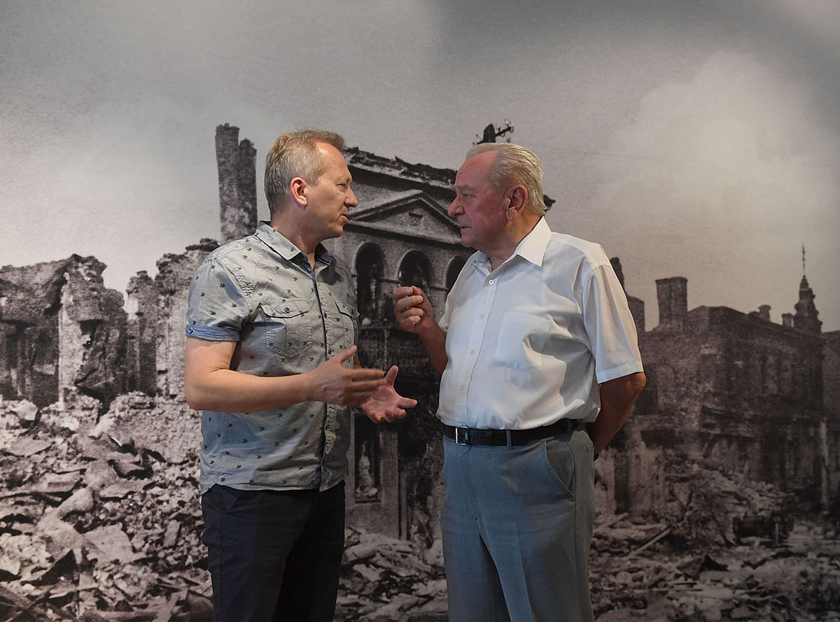 Jan Ksiazek, a historian and director of a local museum talks with historian Tadeusz Olejnik in front a picture of the destroyed town in Wielun, Poland on 20 August 2019. Photo: AFP