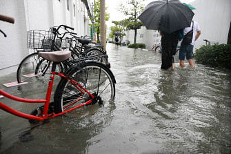 People walk in a flooded street after heavy rains near Saga station in the southwestern city of Saga on August 28, 2019. Japanese authorities on August 28 issued a rare evacuation order for 240,000 people in the country`s southwest over flood and landslide fears, as officials confirmed a man was killed in heavy rains. Photo: AFP