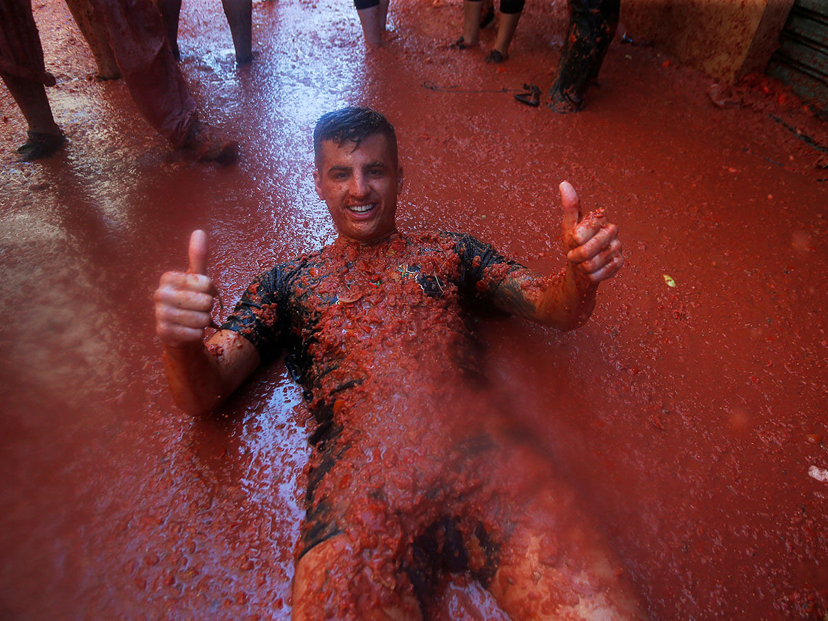 A reveller gives a thumbs up as he lies in tomato pulp during the annual `La Tomatina` food fight festival in Bunol, near Valencia, Spain, on August 2019. Photo: Reuters
