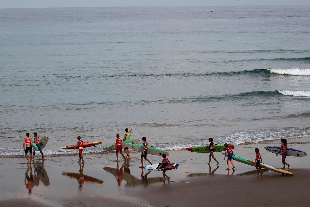 Youngsters carry their surfboards as they attend a class on the Cote des Basques beach in the south-western seaside town of Biarritz, France on 26 August 2019. Photo: AFP