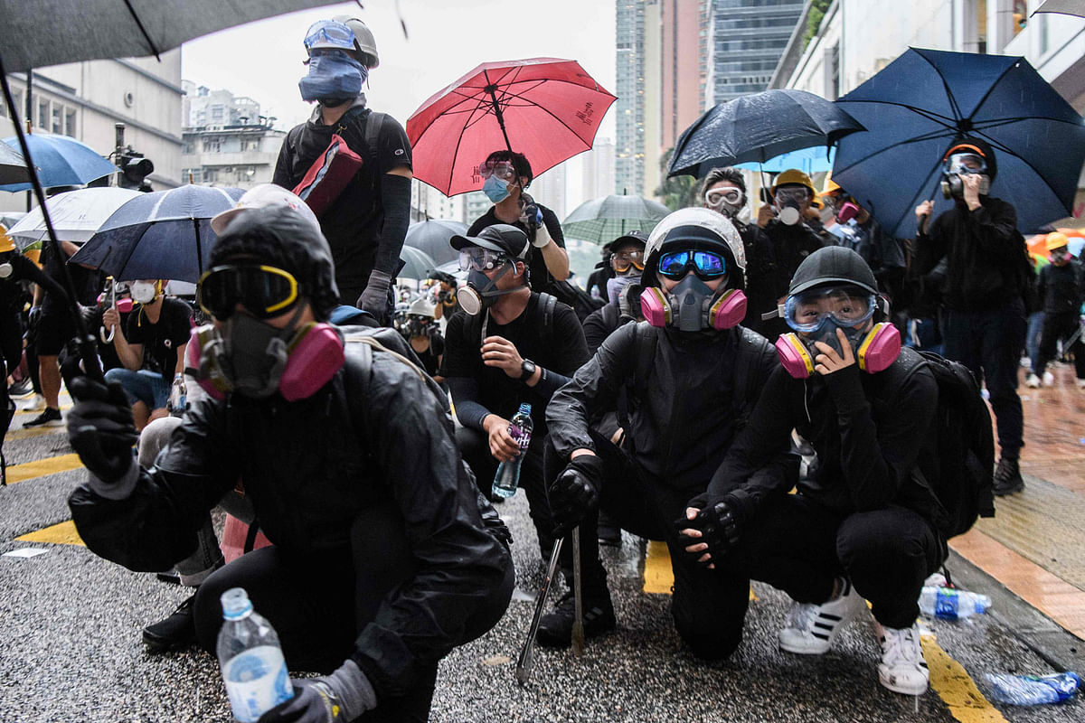 In this picture taken on 25 August 2019, Abby (front R), 19, and her boyfriend Nick, 20, (front 2nd R) crouch down while holding hands as they wait for police to fire tear gas during a protest in Tsuen Wan, an area in the New Territories in Hong Kong. Photo: AFP