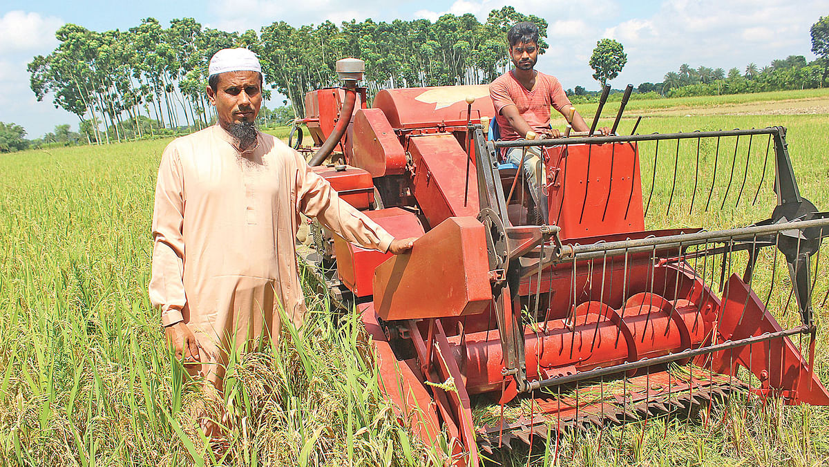 M Ole Ullah along with a combined harvester in Shapur area of Chuadanga. Photo: Prothom Alo