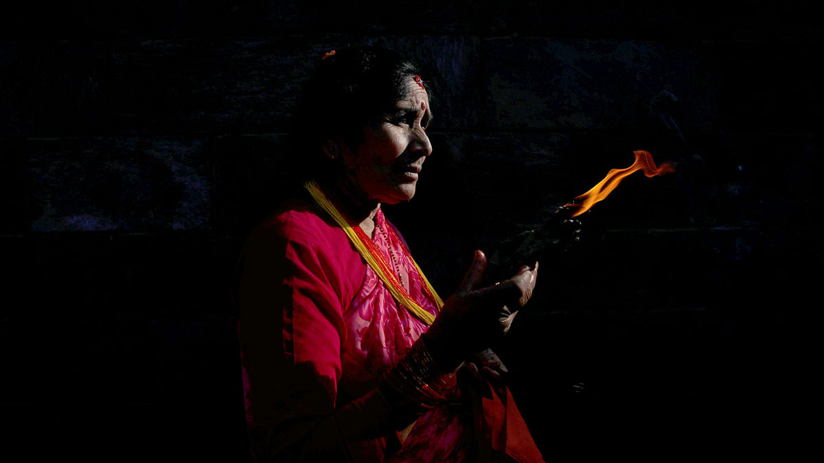 Light illuminates a woman as she offers prayers holding a lamp at the premises of Pashupatinath Temple during the Teej festival in Kathmandu, Nepal on 2 September 2019. Photo: AFP