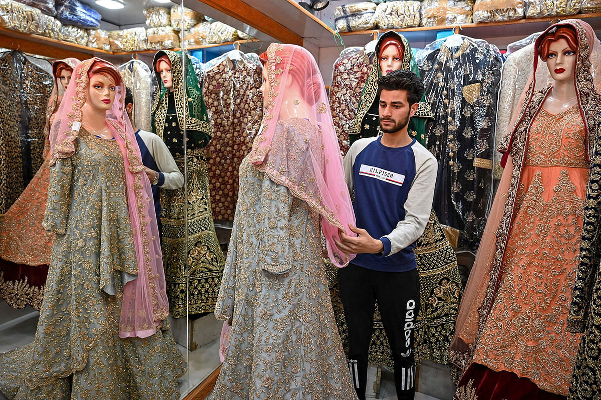 In this file picture taken on 3 June, a Kashmiri shopkeeper displays a wedding dress at a market ahead of the Muslim festival of Eid al-Fitr in Srinagar. Photo: AFP