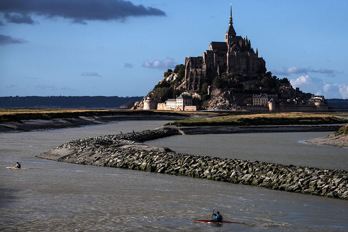 A picture taken on 1 September 2019, shows people kayaking near the Mont-Saint-Michel in Normandy, northwestern France. Photo: AFP