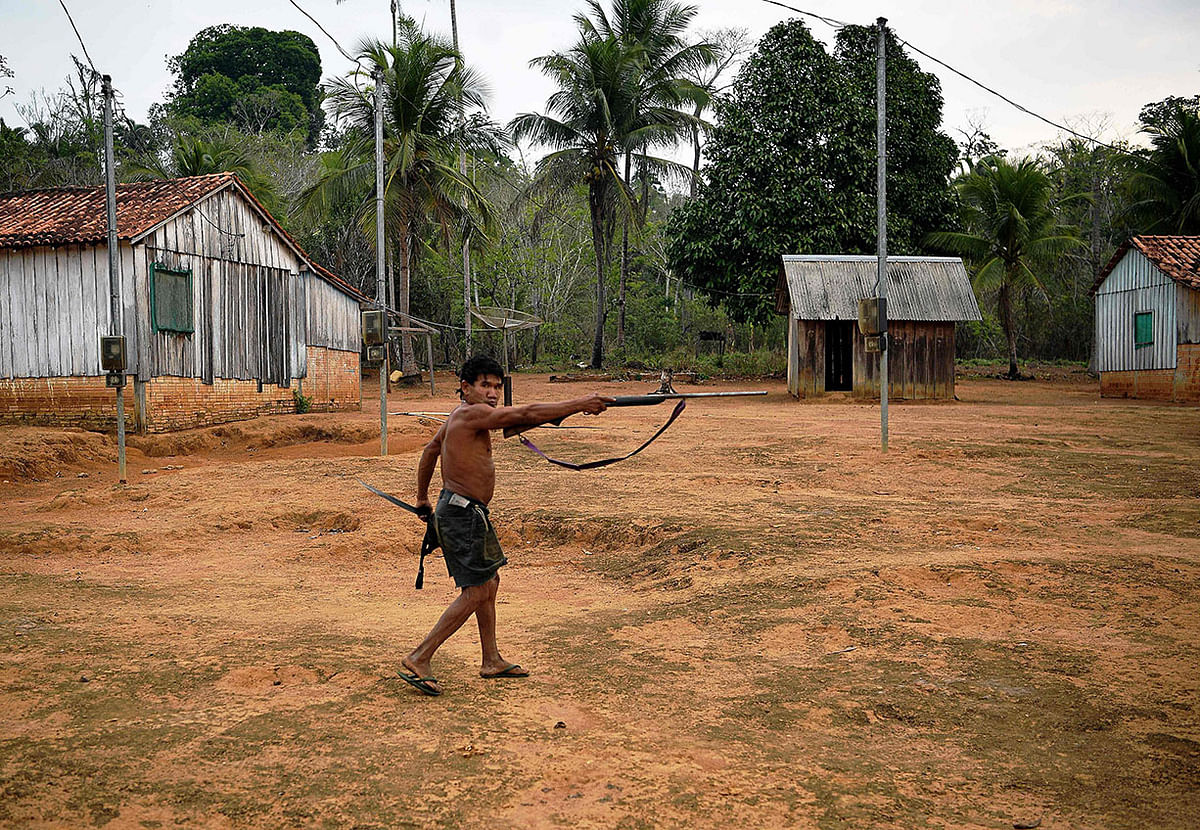 A member of Uru Eu Wau Wau tribe holds up a rifle in the tribe`s reserve in the Amazon, south of Porto Velho, Brazil, on 29 August, 2019. Photo: AFP