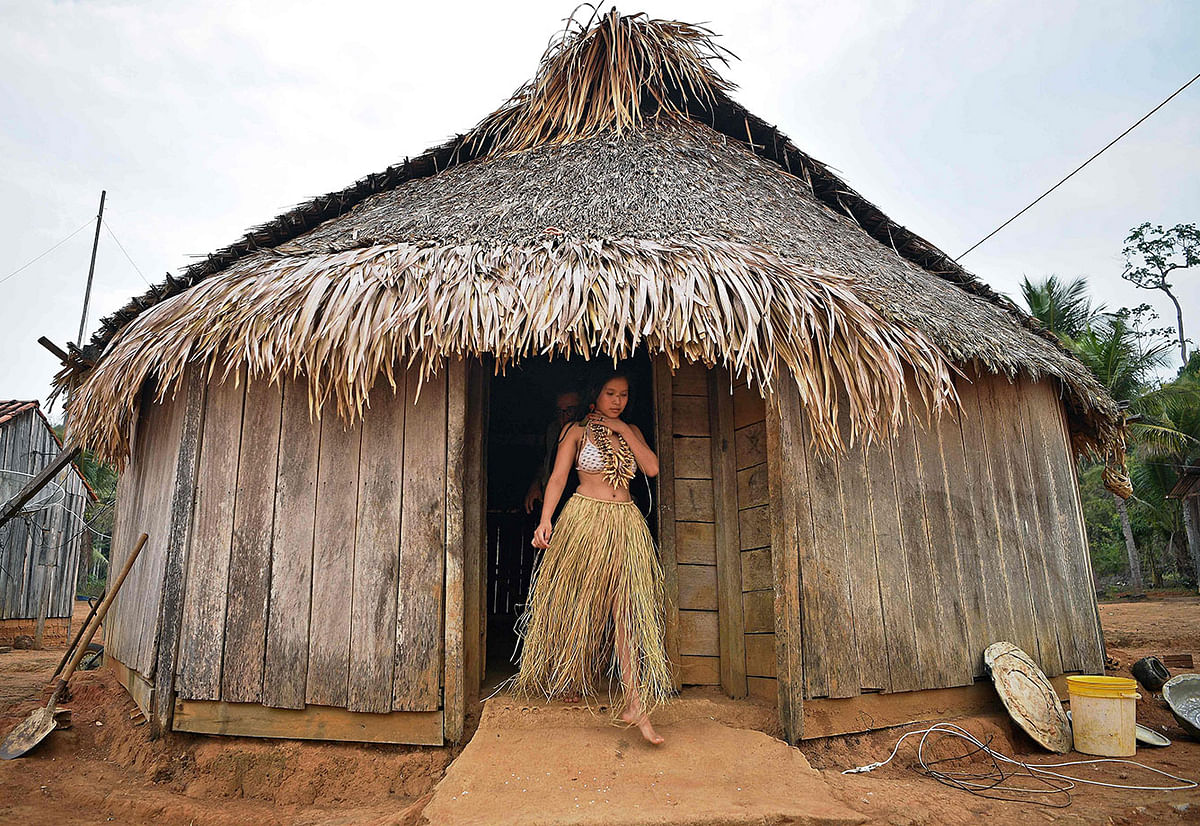 A young woman from the Uru Eu Wau Wau tribe gets out from a straw-thatched hut in the tribe`s reserve in the Amazon, south of Porto Velho, Brazil, on 29 August, 2019. Photo: AFP