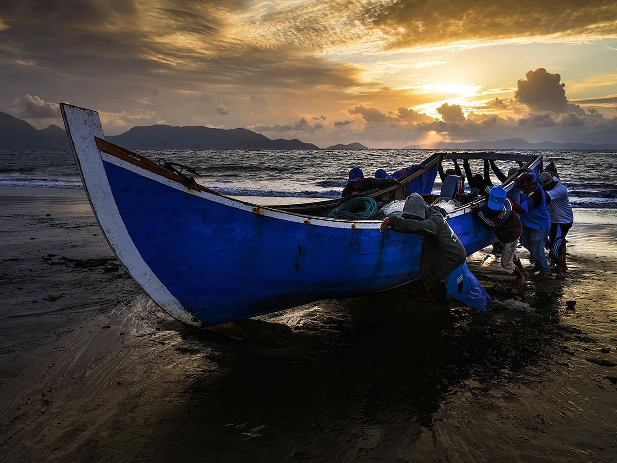 Fishermen push their boat onto the shore upon returning from the sea as the sun sets in Banda Aceh on 3 September 2019. Photo: AFP