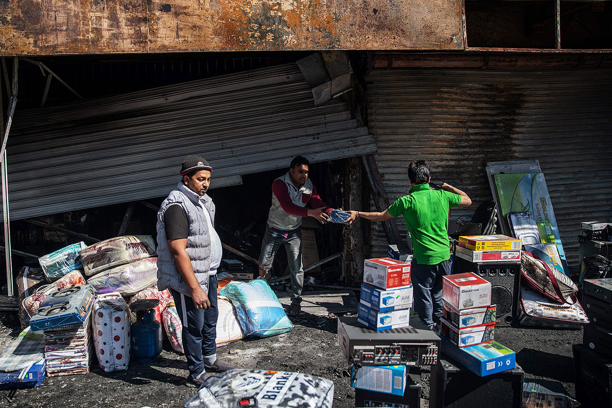 Bangladeshi Kamrul Hasan (green T-shirt) among foreign shop owners check the damages to their looted shop in the Alexandra township of Johannesburg on 3 September 2019 after South Africa`s financial capital was hit by a new wave of anti-foreigner violence. Photo: AFP