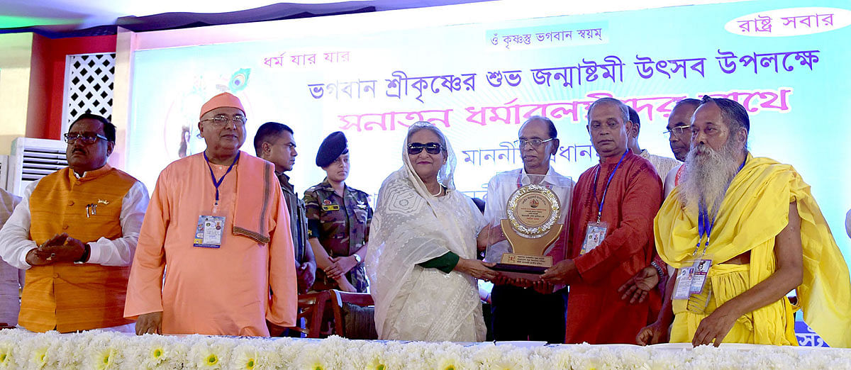 Mahanagar Sarbajanin Puja Udjapon Committee leaders on Wednesday present a crest to prime minister Sheikh Hasina marking the occasion of Janmashtami, the birthday of Lord Sri Krishna. Photo: PID