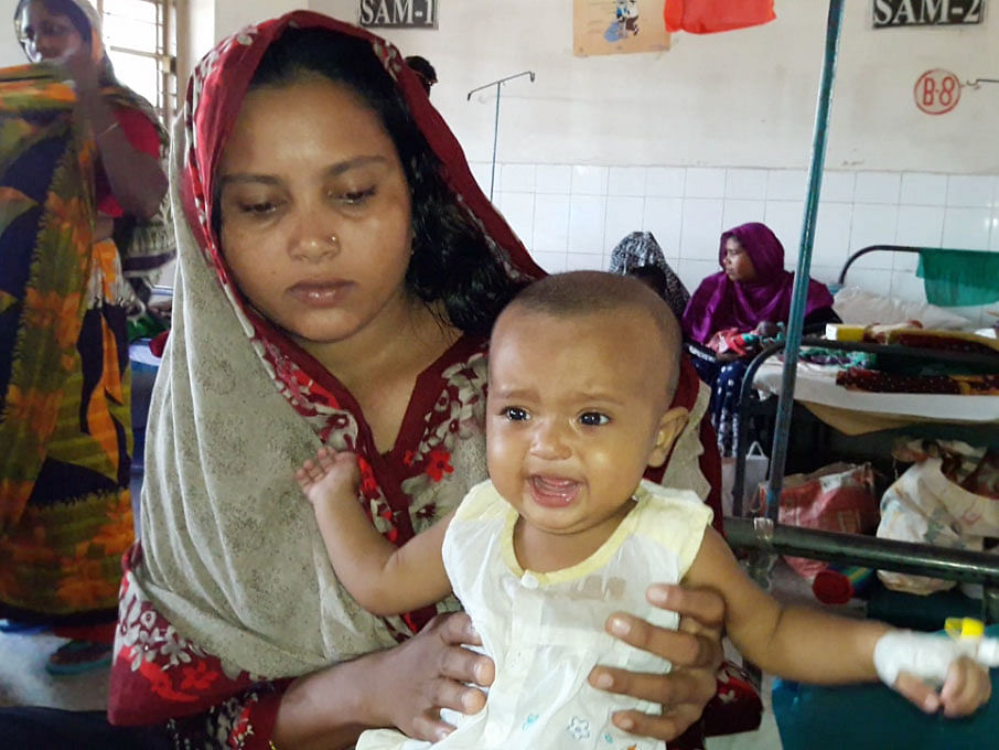 A baby cries as her mother waits in the queue to see the physician. Photo: UNB