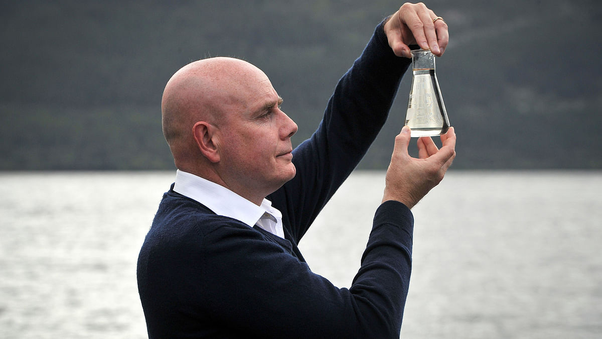University of Otago geneticist, Professor Neil Gemmell poses with a beaker of water on the shores of Loch Ness after announcing the results of investigations into the environmental DNA present in Loch Ness in Drumnadrochit , Scotland, on 5 September 2019. Photo: AFP