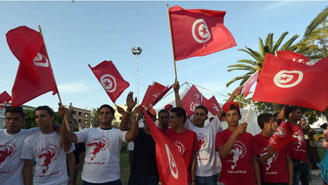 Supporters of the Destour Movement wave the national flag during a meeting of the former prime minister, Hamed Karaouihis, as he campaigns in Menzel Temim on 18 October 2014. Photo: AFP