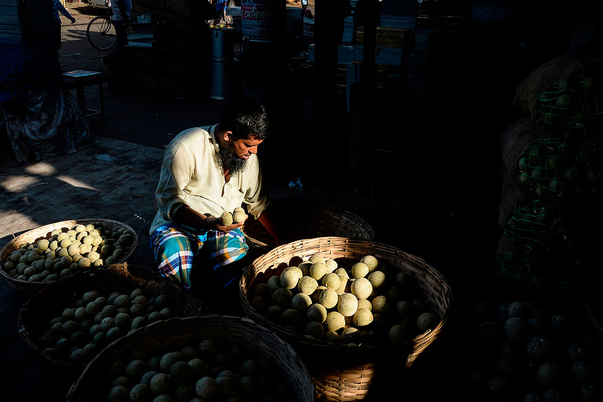 A vendor arranges wood-apples at Kawran Bazar wholesale market in Dhaka on 8 September, 2019. Photo: AFP