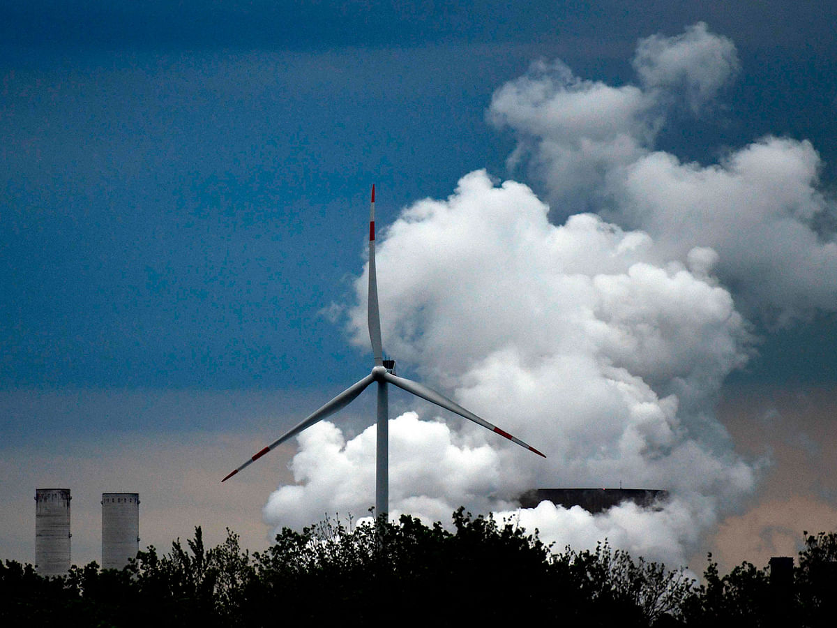 a wind turbine stands in front of a coal-fired power plant of German energy giant RWE near Niederaussem, western Germany. Wind power is a key pillar in Germany`s ambitious renewables transition plan, but the sector has struck strong resistance, forcing the Chancellor Angela Merkel`s government to open talks on the crisis on 5 September 2019. AFP file photo