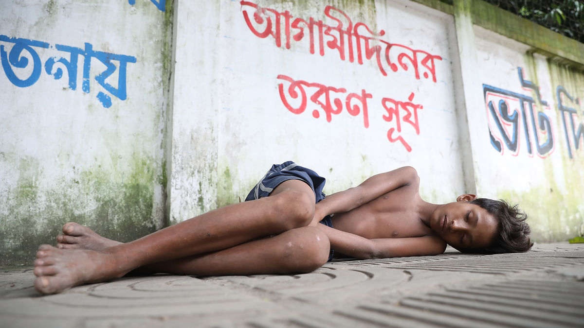 A boy sleeps on the footpath at Dhaka University campus, 10 September 2019. Photo: Abdus Salam