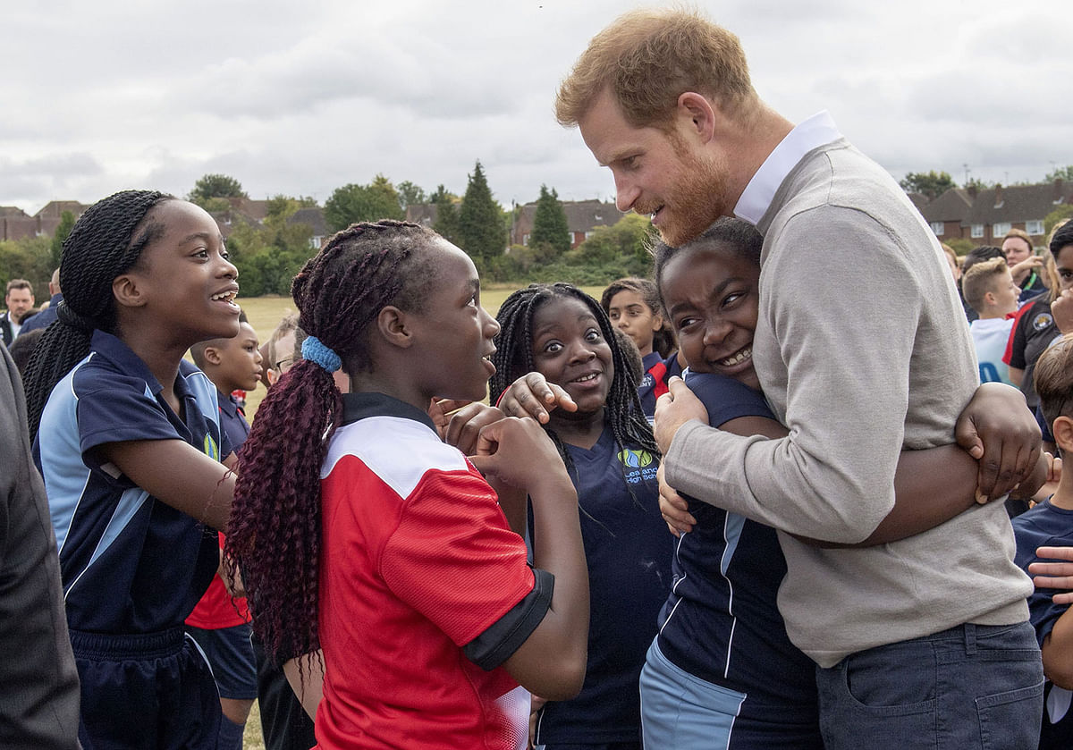 Pritain`s Prince Harry, Duke of Sussex gets a hug from Zara Jess Gudza (2R) as he meets participants during his visit to the Rugby Football Union (RFU) All Schools programme at Lealands High School in Luton, south east Bedfordshire on 12 September, 2019. Photo: AFP